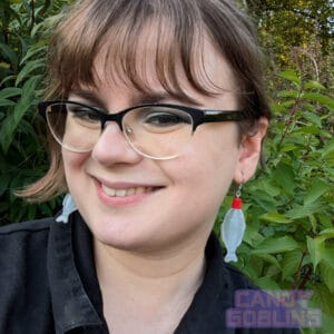 A model wears our soy sauce bottle earrings, while smiling. The bottles are the kind you would usually find included in takeaway sushi