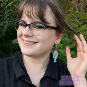 A model wears our soy sauce bottle earrings, while smiling. The bottles are the kind you would usually find included in takeaway sushi