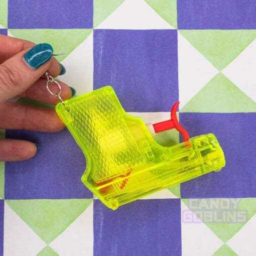 Someone holds a yellow water pistol earring, against a funky background