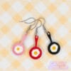 Our egg pan earrings are displayed together. The pans are red, black, and pink, and all have an egg frying on the surface.
