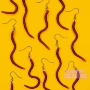Many worm earrings lie against a yellow background. The worms are wiggled in a bunch of different shapes and look realistic.