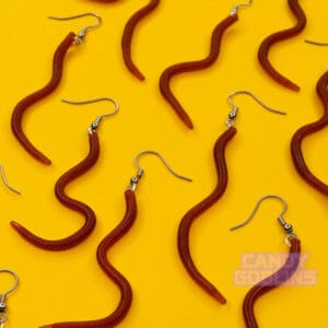 Many worm earrings lie against a yellow background. The worms are wiggled in a bunch of different shapes and look realistic.