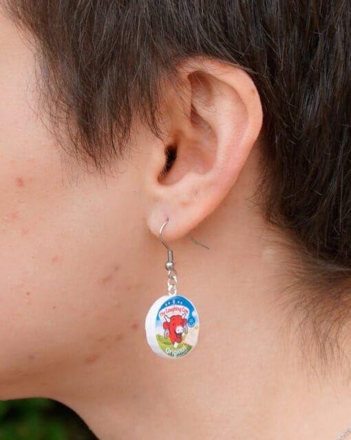 A person wears a Laughing Cow earring