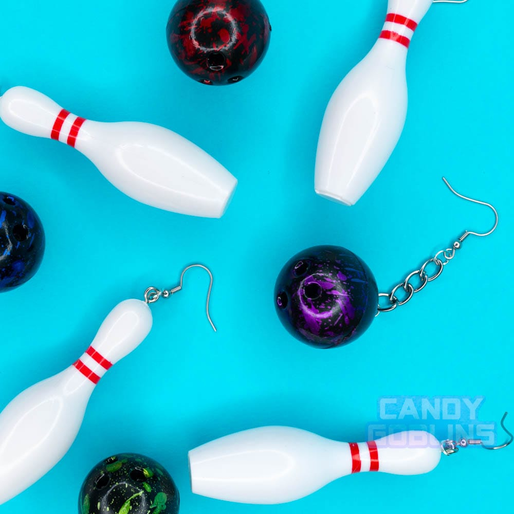 Bowling earrings are scattered across the backdrop, you can see the different coloured bowling balls, purple, green, and red.