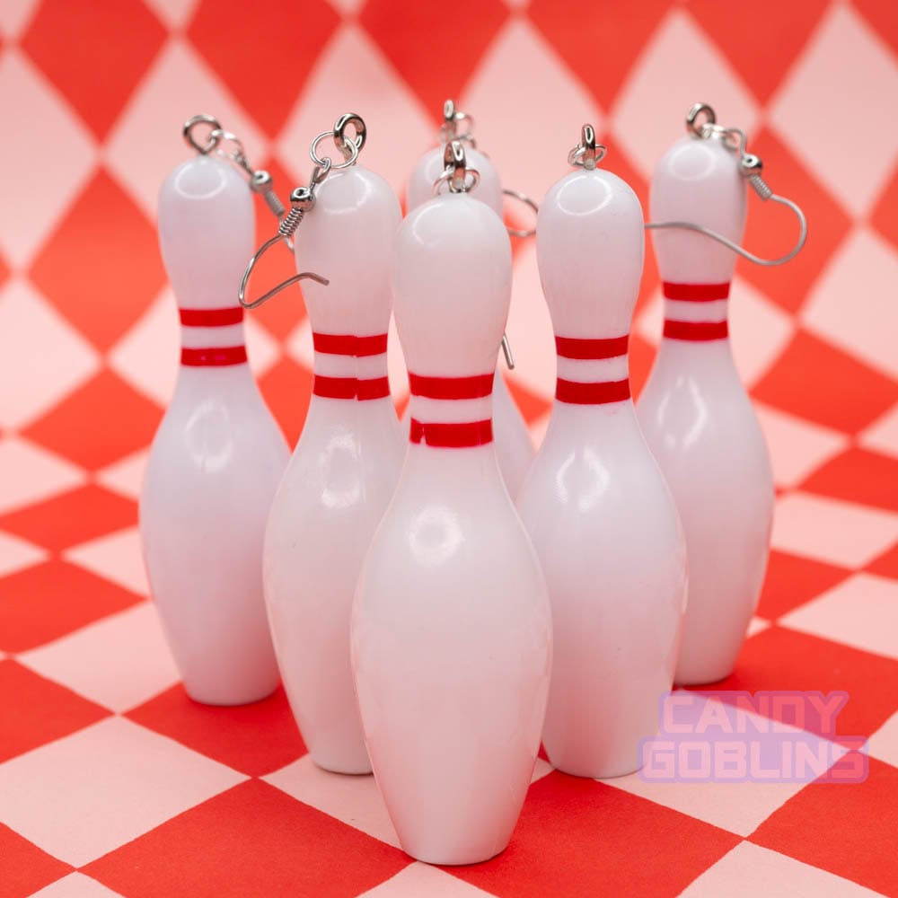 Several bowling pin earrings are lined up, like pins would be at a bowling alley