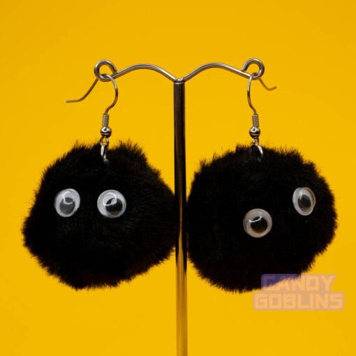 Black soot sprite earrings dangle from a silver earring display. The googly eyes on the sprites stand out like they're looking at you.