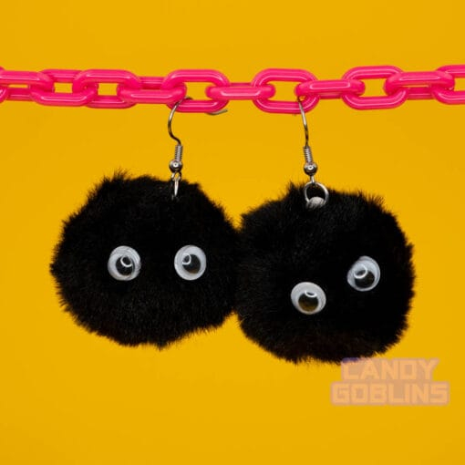 Black soot sprite earrings dangle from a pink chain display. The googly eyes on the sprites stand out like they're looking at you.