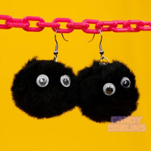 Black soot sprite earrings dangle from a pink chain display. The googly eyes on the sprites stand out like they're looking at you.