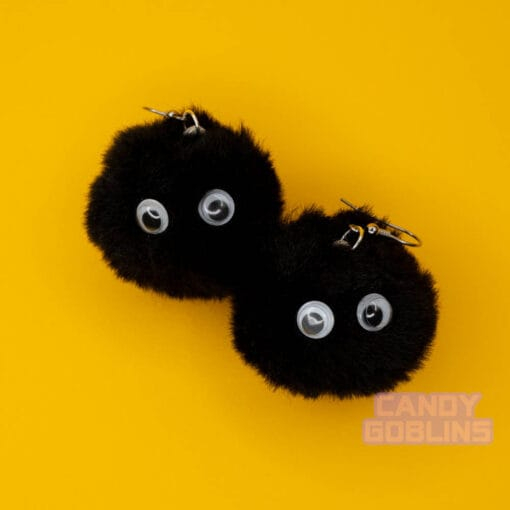 A pair of soot sprite earrings stare with googly eyes in their black fur