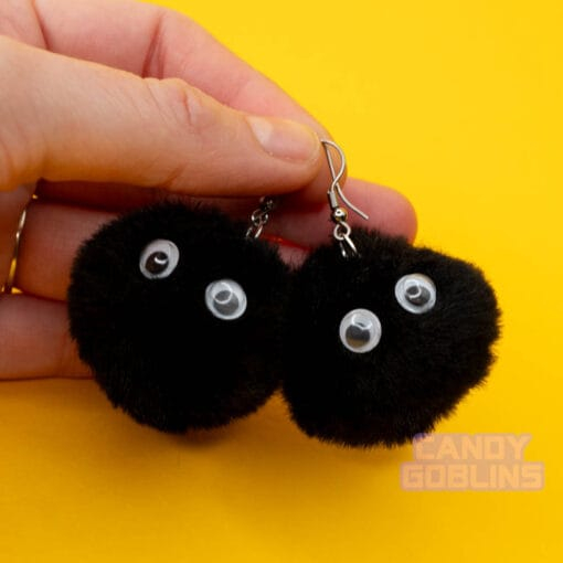 A hand holds a pair of our soot sprite earring by the hook