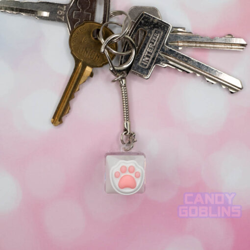 A cat keycap keychain featuring a white paw, with pink beans