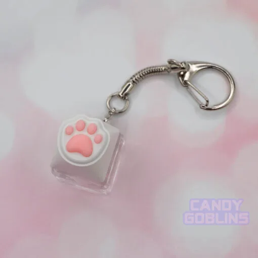 A cat keycap keychain featuring a white paw, with pink beans