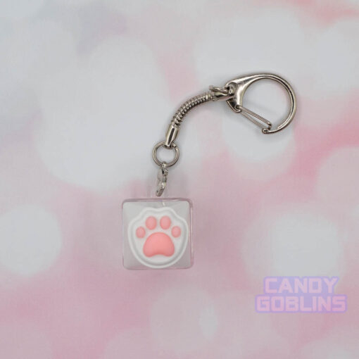 A cat keycap keychain featuring a white paw, with pink beans