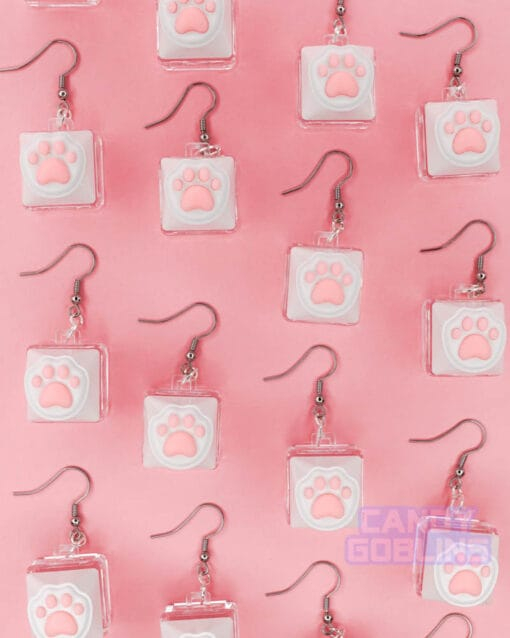 Multiple of our Cat Keyboard Switch Earrings are laid out together. The background is a pastel pink.