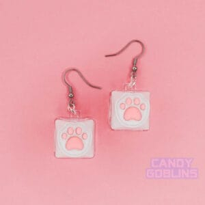 A pair of our Cat Keyboard Switch Earrings. The background is a pastel pink.