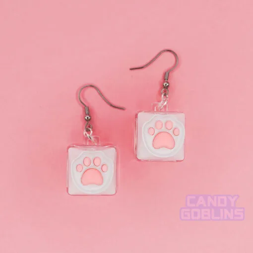 A pair of our Cat Keyboard Switch Earrings. The background is a pastel pink.