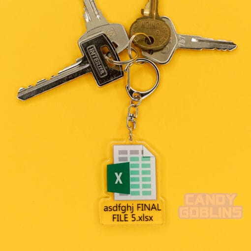 Our Excel Keychain is attached to a pair of keys. They're lying on a yellow background. The keychain features the Microsoft Excel logo, with text underneath that reads "asdfghj FINAL FILE 5.xlsx"