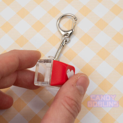 A person pressing down on a red Keyboard Switch Keychain