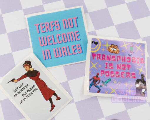 Three of our queer and Welsh sticker designs laid out on a backdrop