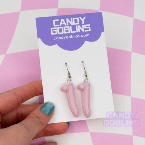 A pair of pink dildo earrings on our Candy Goblins packaging