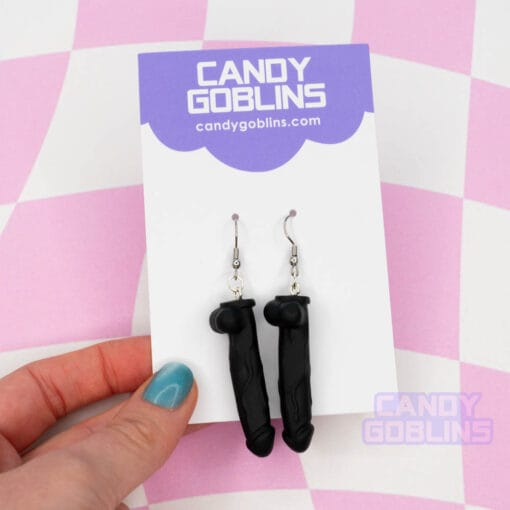 A pair of black dildo earrings on our Candy Goblins packaging