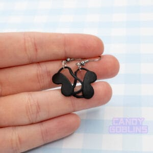 A pair of eye mask earrings being held by someone