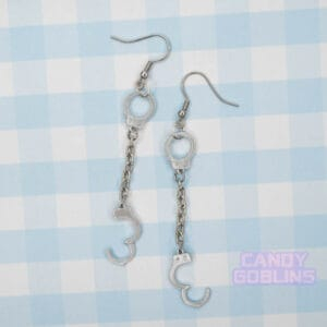 A pair of handcuff earrings, they have a metal chain connecting the cuffs