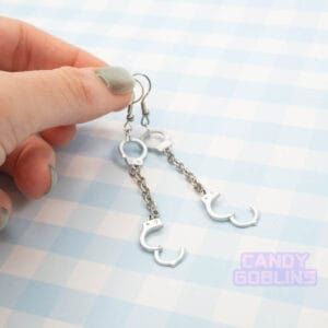 A pair of handcuff earrings, they have a metal chain connecting the cuffs