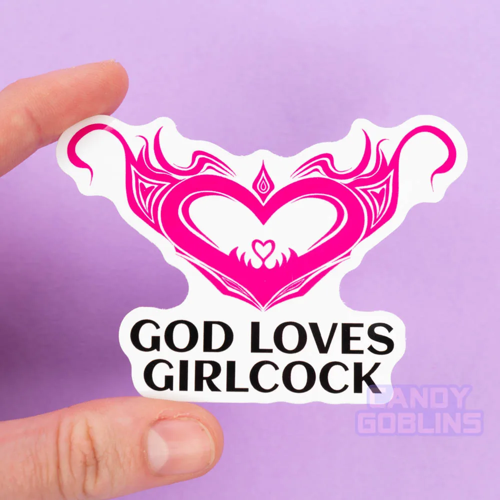 A person holds a sticker of a hot pink womb heart design. The text underneath reads "god loves girlcock"