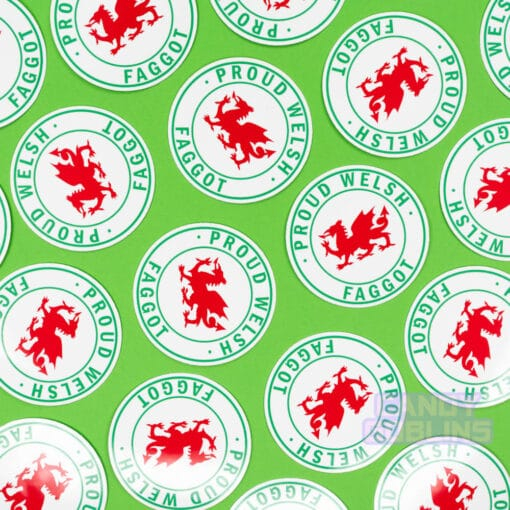 Stickers are scattered across a green background. The stickers have Welsh dragons on them, and text around it reads "Proud Welsh Faggot"