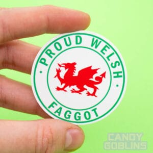 A person holds up a circle sticker with a Welsh dragon in the middle, text around it reads 