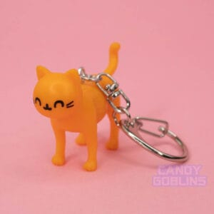 An orange cat keychain looks at the camera with a content and happy expression