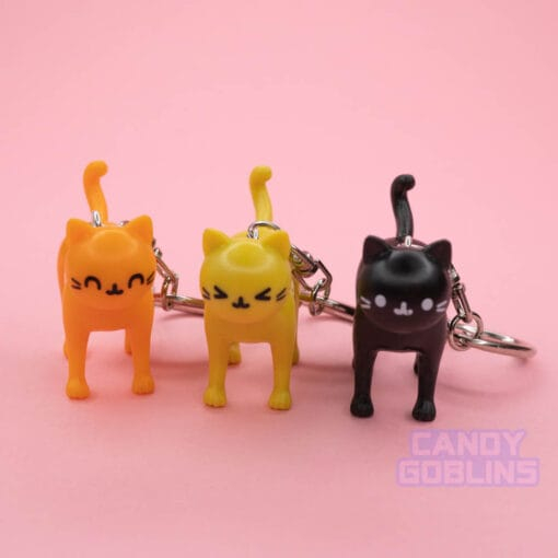 A row of cat keychains, featuring a orange cat, a yellow cat, and a black cat
