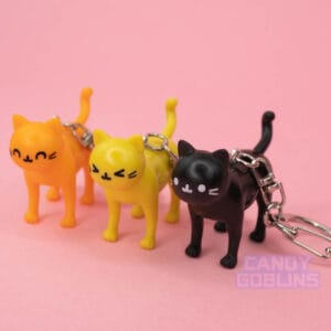 Three cat keychains are lined up, each with a different expression on the cats face