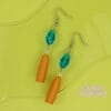 A pair of our Revolver Earrings lie against a photo prop