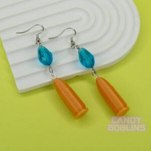 A pair of our Revolver Earrings lie against a photo prop