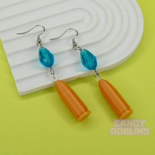 A pair of our Revolver Earrings lie against a photo prop