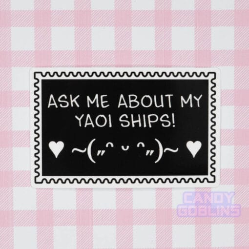 A stamp shaped sticker reads: Ask Me About My Yaoi Ships. Under the text is a happy emoticon, blushing and dancing with hearts. It's against a pink background.