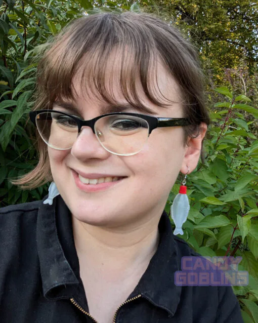 A model wears our soy sauce bottle earrings, while smiling. The bottles are the kind you would usually find included in takeaway sushi