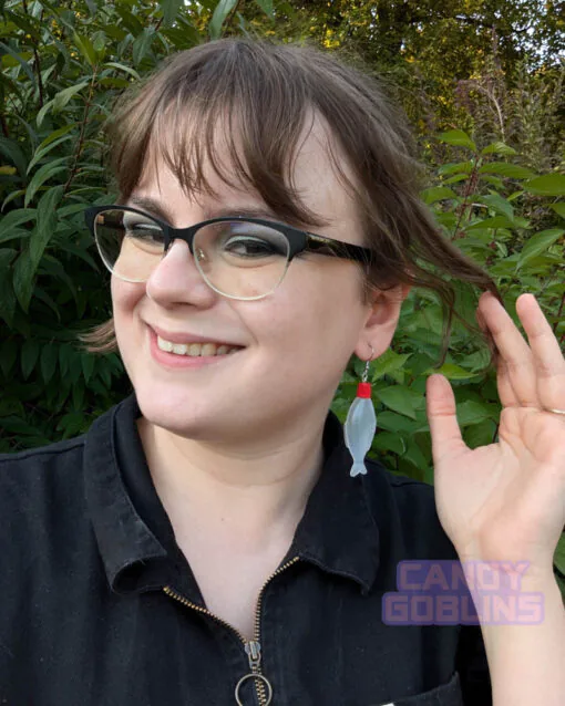 A model wears our soy sauce bottle earrings, while smiling. The bottles are the kind you would usually find included in takeaway sushi