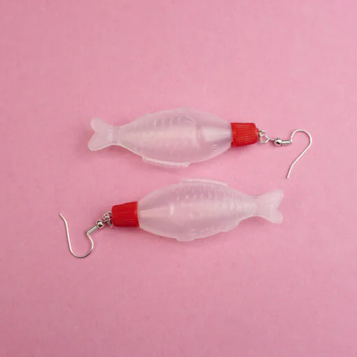 A pair of soy sauce earrings against a pink backdrop